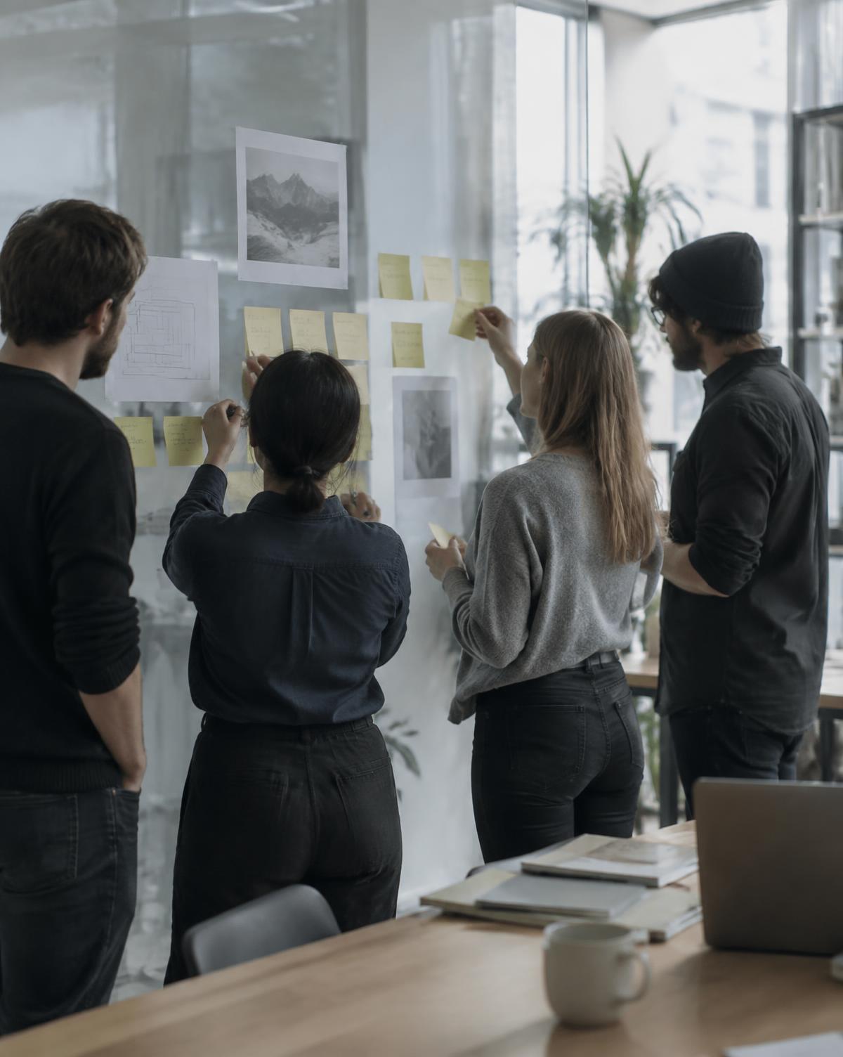 A team arranging notes on a glass wall during a workshop